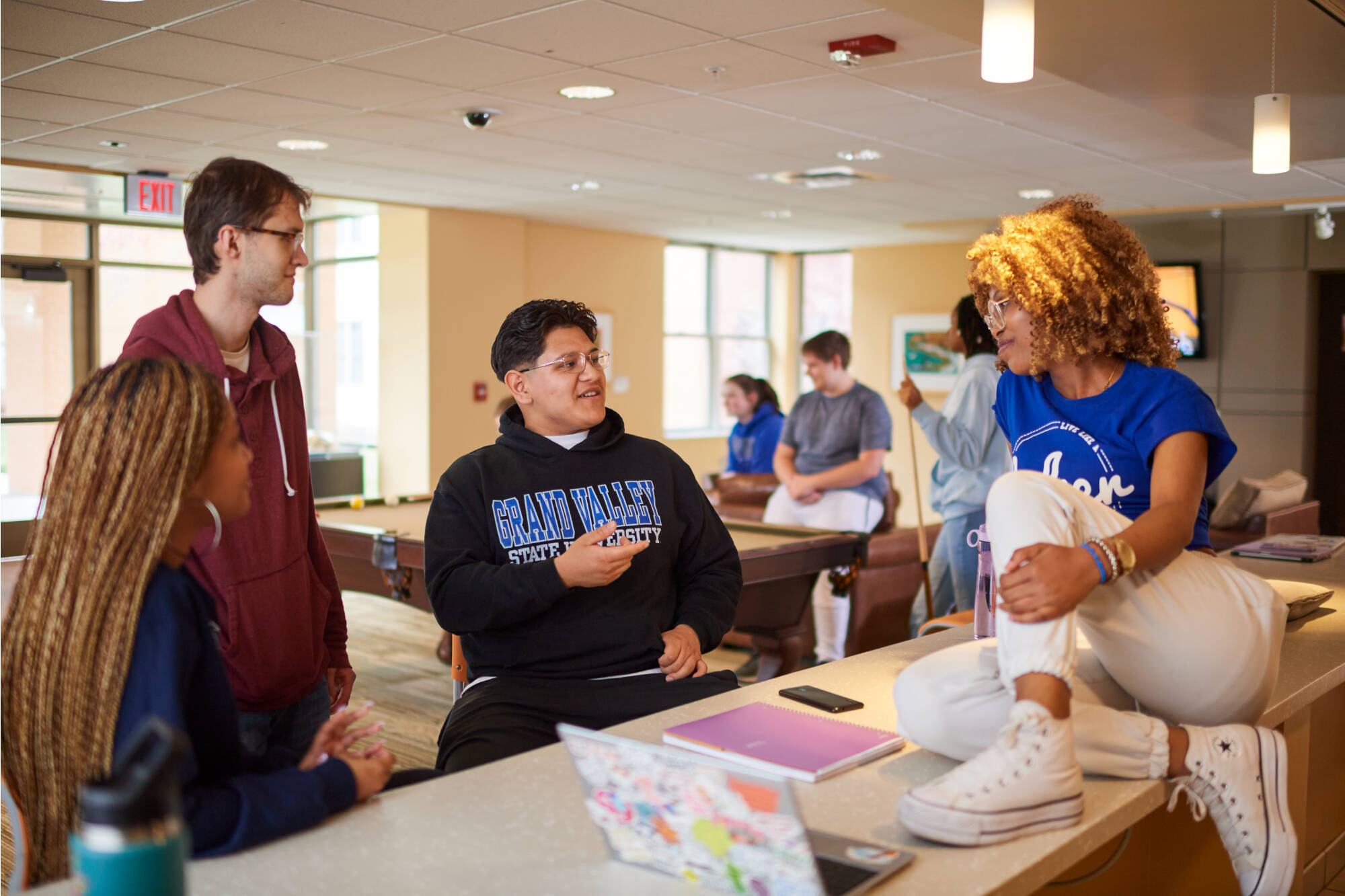 Students around a table in the South E lounge talk and collaborate.